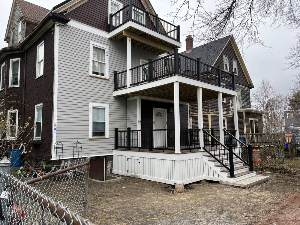 New two-story rear porch with black railings and white skirting on a Victorian home
