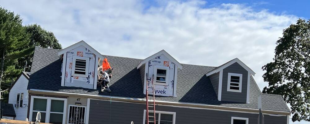 Crew installing gray siding and trim on the dormers