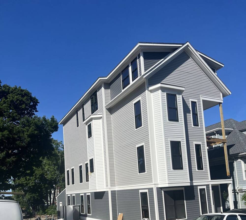 Three-story house with new gray siding, white trim and bay windows