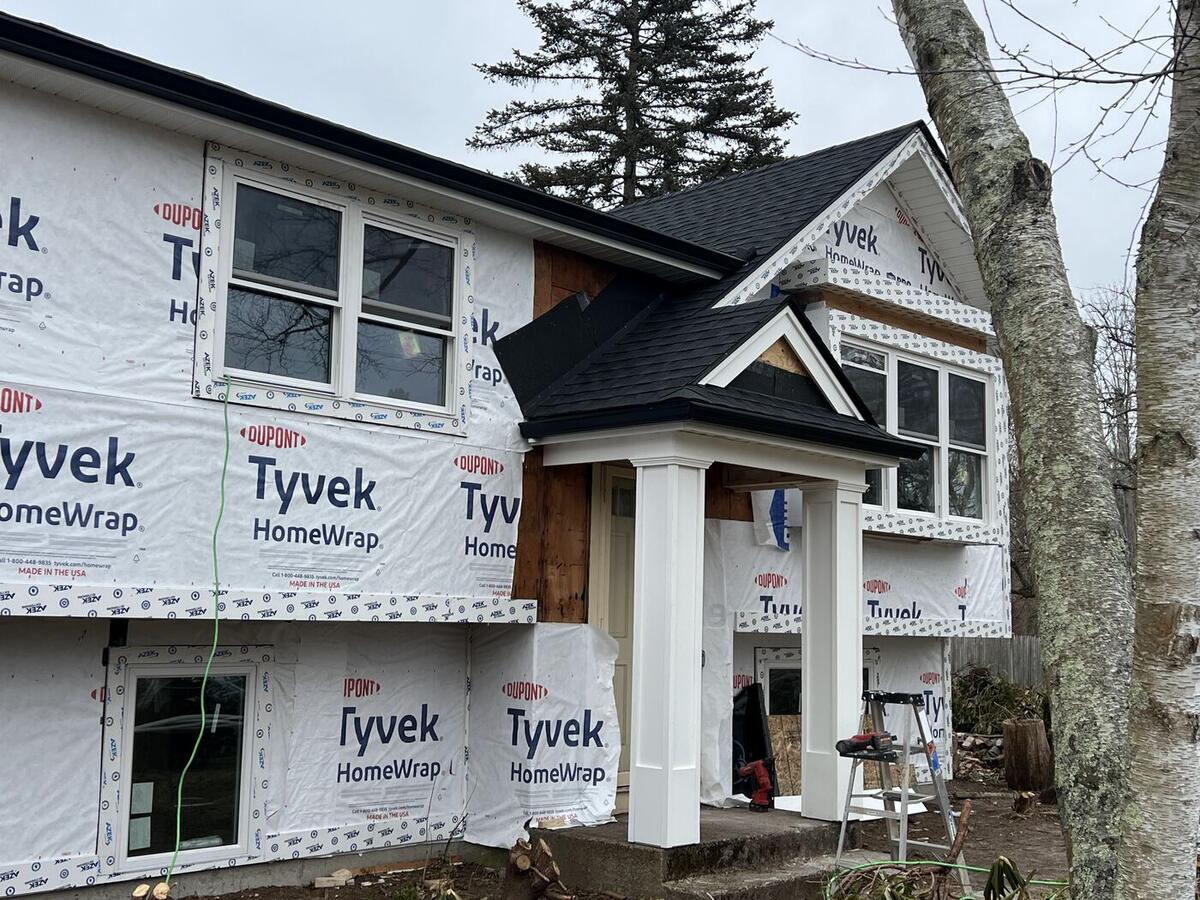 New entry portico with white columns and black shingle roof