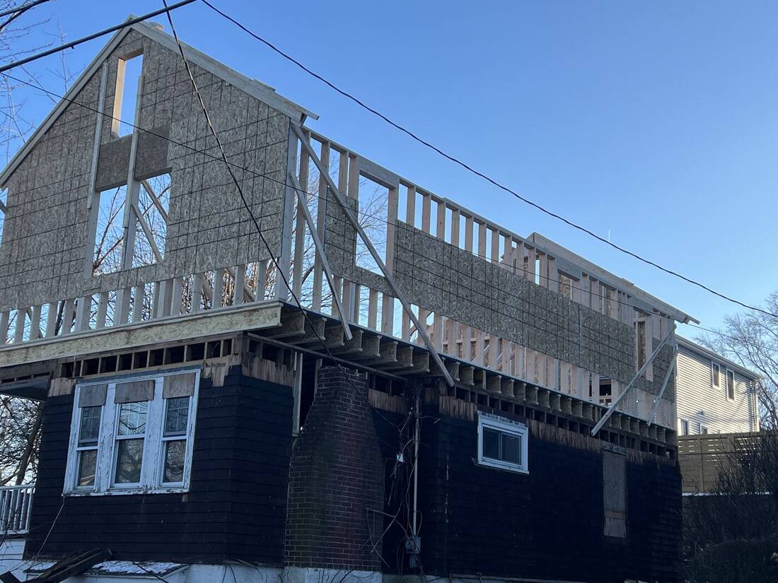 New second-story walls and gable framed above the existing house