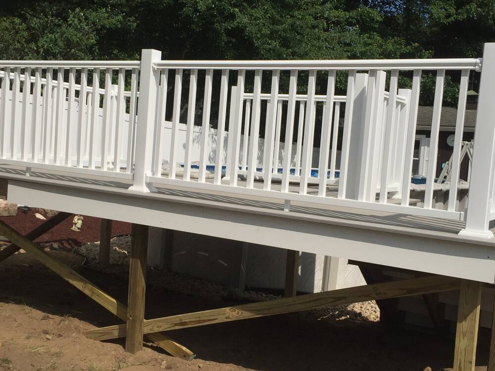 Pool deck railings and braced post framing seen from the yard