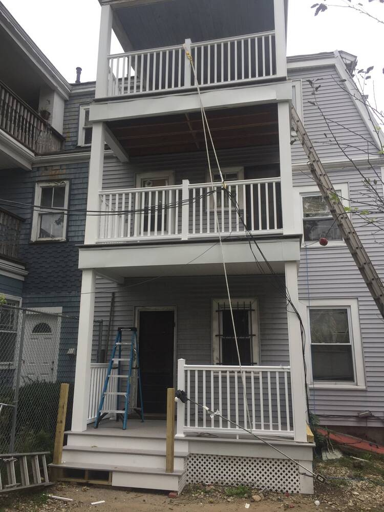 New three-story rear porches with white columns, trim and railings