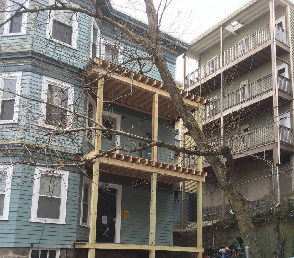 New pressure-treated posts and joists for two stacked front porches