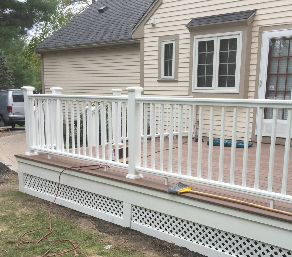 Brown composite decking with white vinyl railings being installed