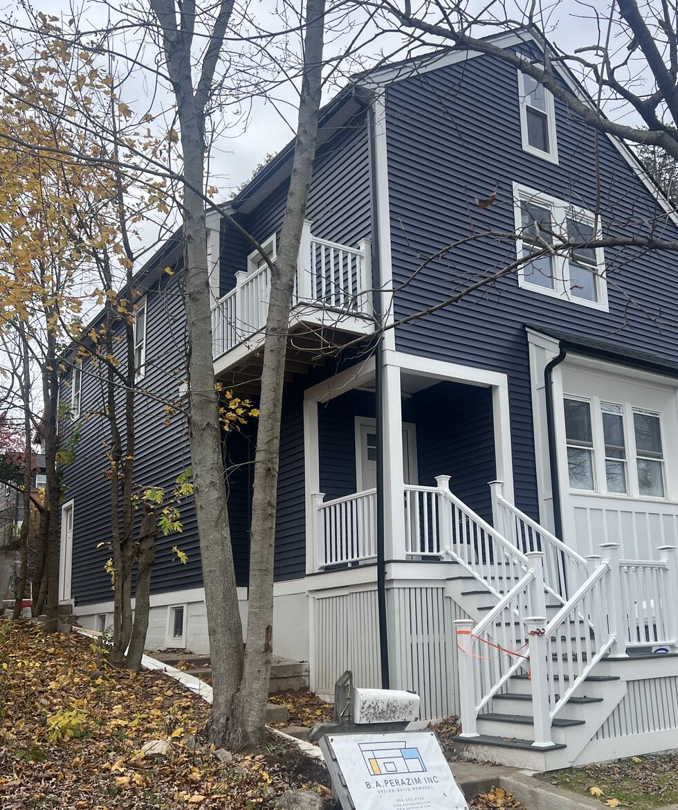 Two-story home addition with navy siding, front porch and balcony, built by B.A. Perazim