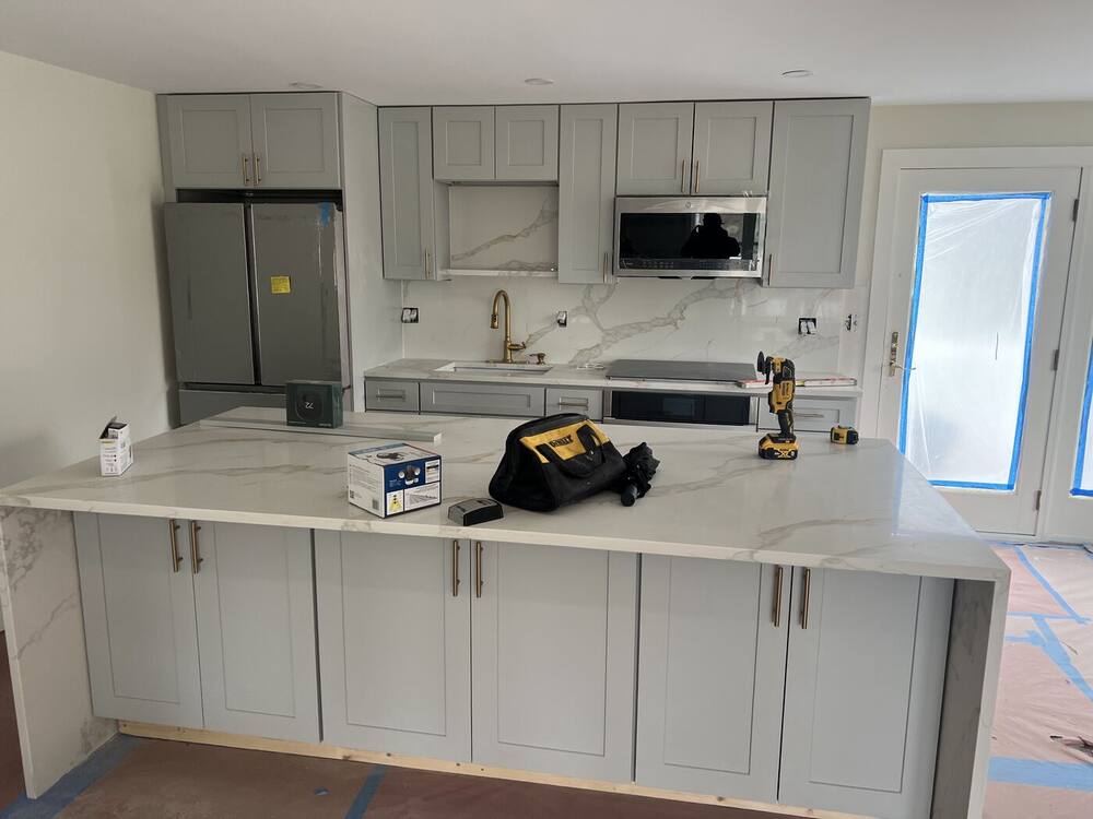 Gray shaker cabinets and white quartz waterfall island installed