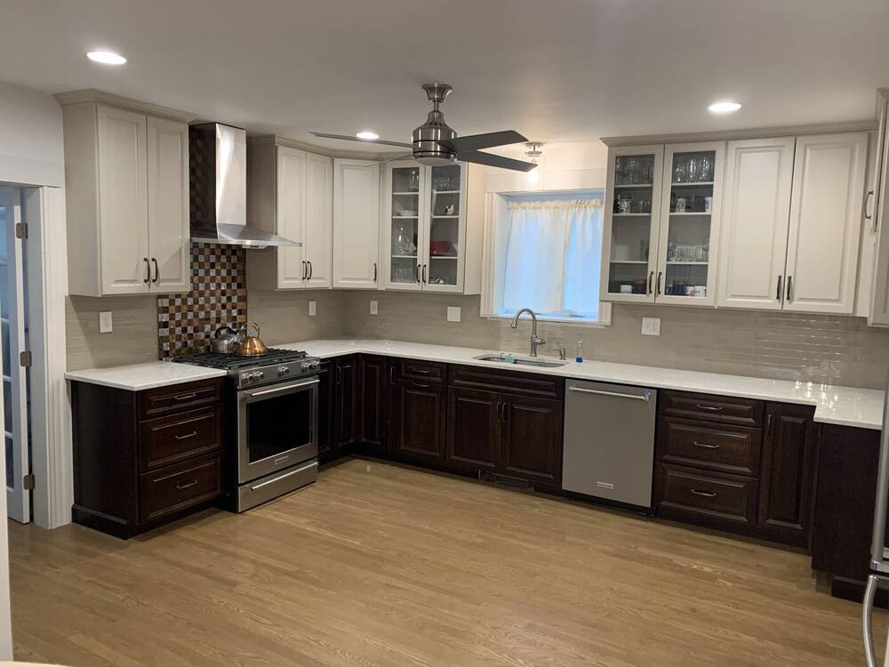 L-shaped kitchen with dark cherry base cabinets, white uppers, stainless range hood and mosaic backsplash