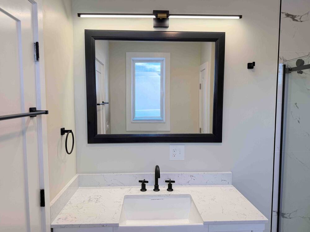 Quartz vanity with matte black fixtures, framed mirror and LED light bar