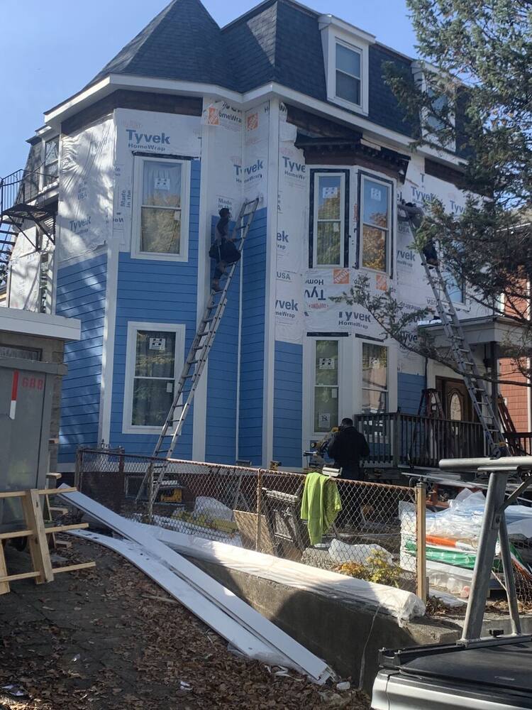 Blue lap siding and white trim being installed over the housewrap