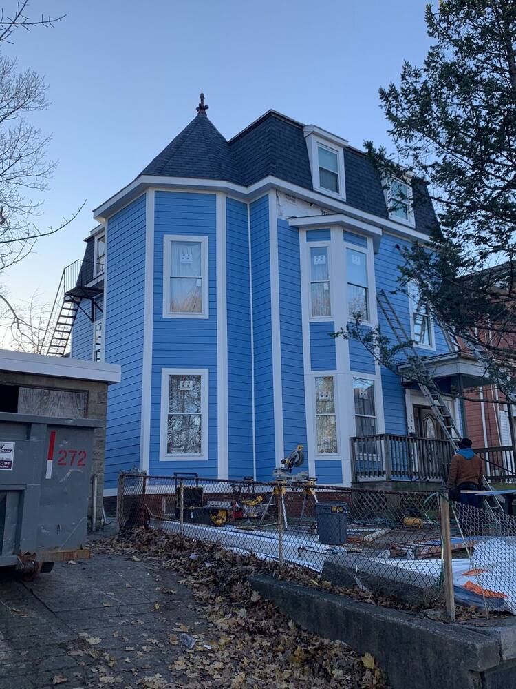 Finished blue siding with white trim on the mansard Victorian