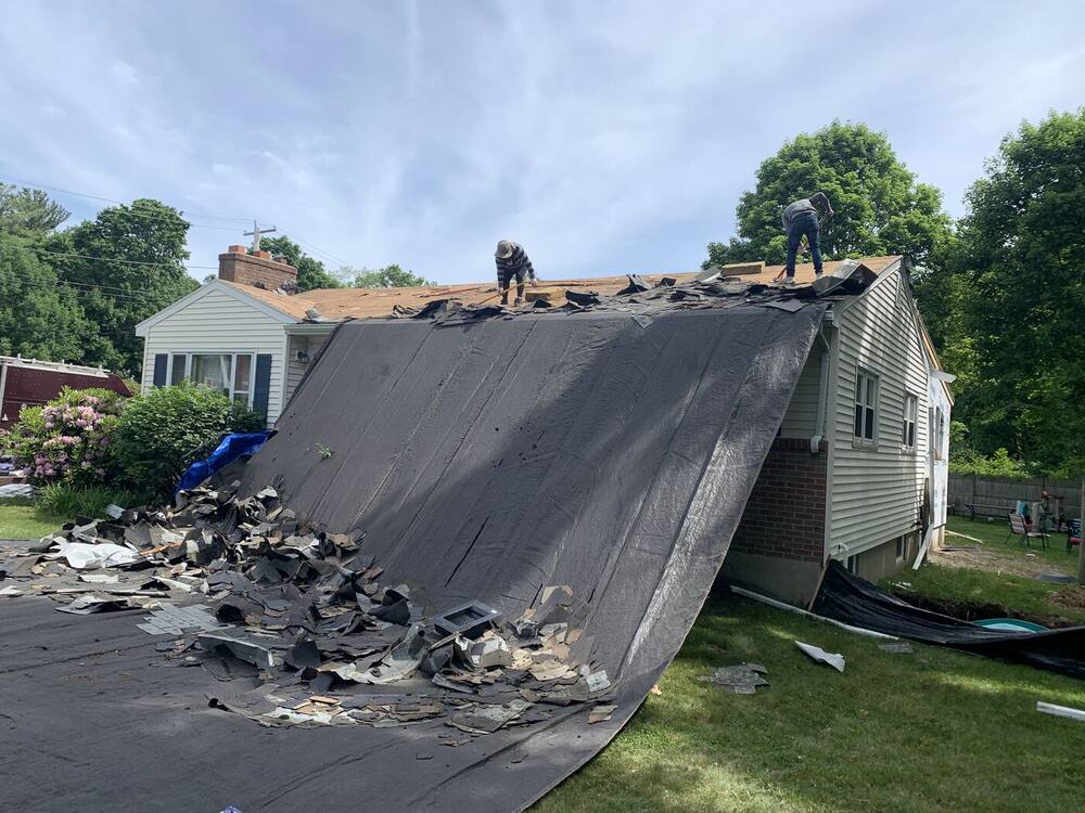 Old shingles torn off a ranch roof onto protective tarps