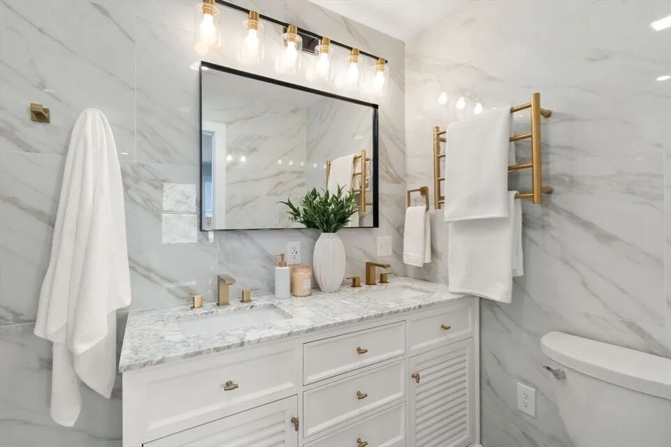 Primary bath double vanity with marble top, brass fixtures and marble-look tile