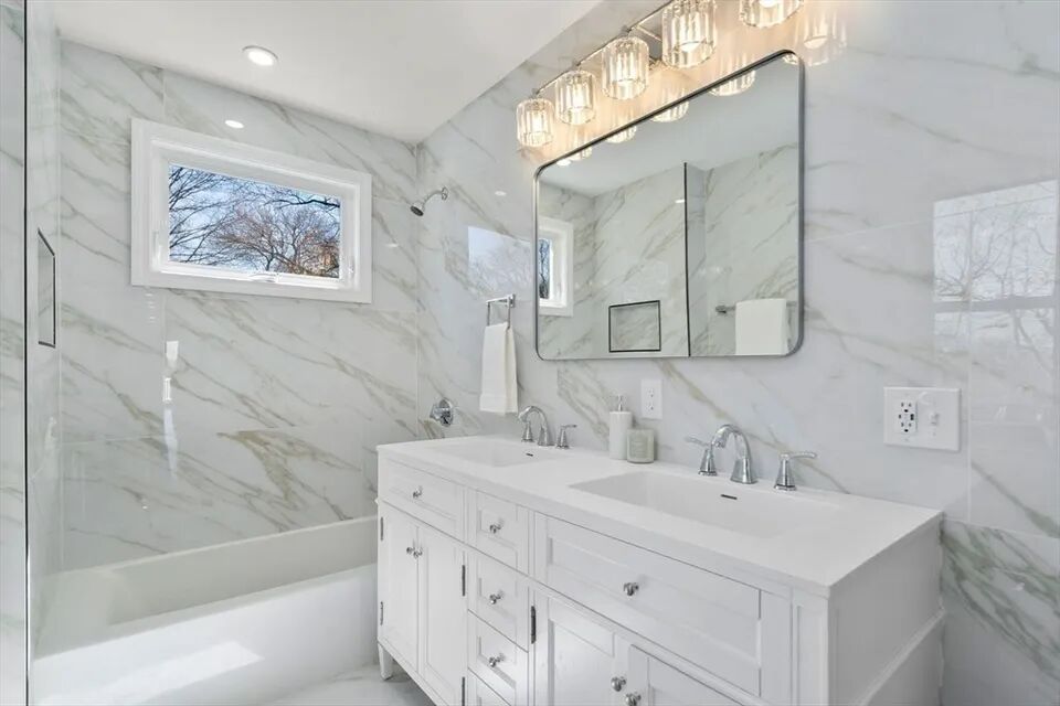 Double vanity, tub with glass panel and floor-to-ceiling marble-look tile
